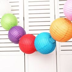 multicolored paper lanterns hanging from the side of a white door