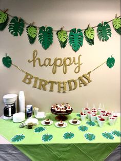 a table topped with cupcakes and desserts next to a happy birthday banner