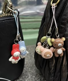 two purses with key chains attached to them sitting next to each other on a table