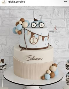 a three tiered cake with blue and brown decorations on it's side, sitting on a table