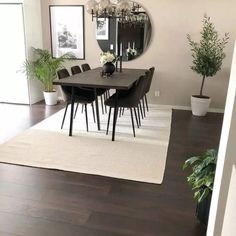 the dining room table is surrounded by chairs and potted plants in front of it