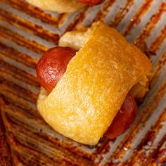 two hotdogs with mustard and ketchup wrapped in bread on a grill