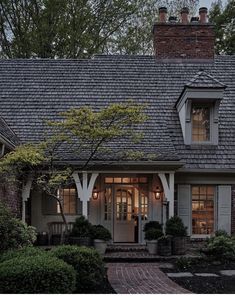 a gray house with white trim and shingles on the roof is lit up at night