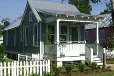 a small house with a white picket fence around it's front yard and porch