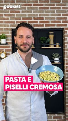 a man standing in front of a brick wall holding a bowl of food with the words pasta e piseli cremosa