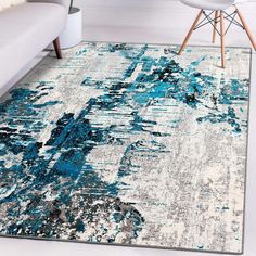 an area rug with blue and white paint splattered on it in a living room