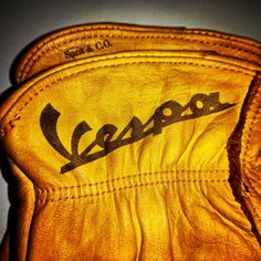 an old yellow leather glove with the word vespa written in black on it