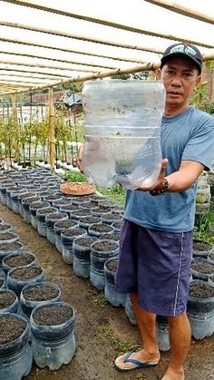 an older man holding a large plastic container filled with dirt and water in his hands