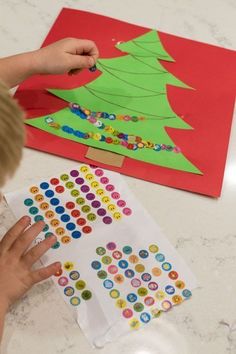 a child is making a christmas tree sticker craft