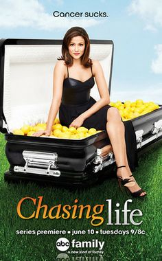 a woman sitting in an open suitcase filled with lemons on top of green grass