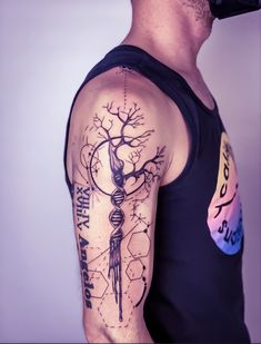 a man wearing a black tank top with a tree and clock tattoo on his arm