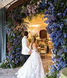 a bride and groom standing in front of a flower covered wall at their wedding reception