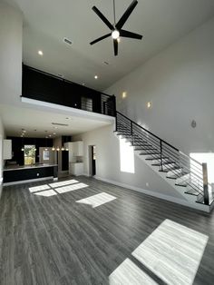 an empty living room with wood flooring and stairs leading up to the second floor