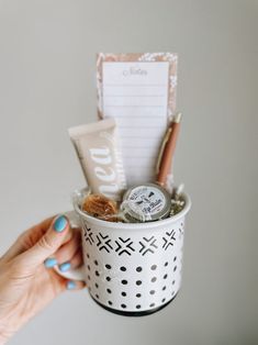 a woman's hand holding a cup filled with items