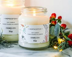 two candles sitting next to each other on top of a white countertop with greenery