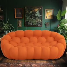 an orange couch sitting on top of a hard wood floor next to potted plants