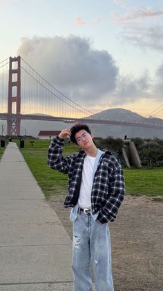 a man standing in front of the golden gate bridge with his hands to his face