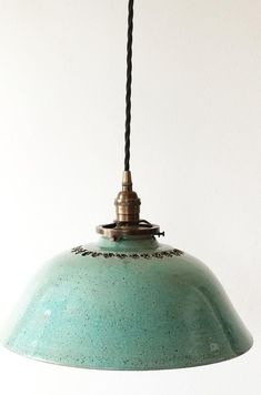 a green light hanging from a ceiling fixture with a black cord attached to the end