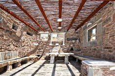 an old stone building with benches and tables in the sun shining through the window frames