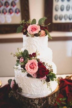 a three tiered wedding cake with pink and red flowers