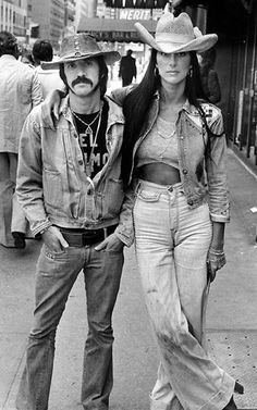 the man and woman are standing on the sidewalk together, posing for a black and white photo