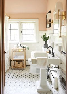 a bathroom with pink walls and white tile on the floor is pictured in this image