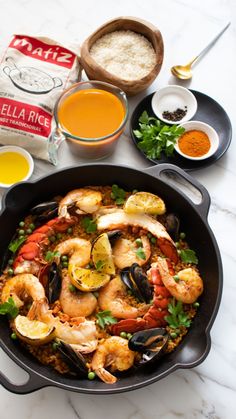 a skillet with shrimp, mussels and rice in it