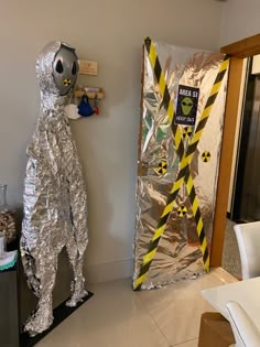 an aluminum foil astronaut standing in front of a door that is taped to the wall