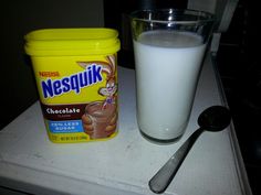 a glass of milk next to a container of nestle nepsupki chocolate