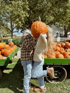 a man and woman standing next to each other in front of a truck full of pumpkins