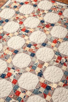 an old quilt is laying on top of a bed sheet that has red, white and blue squares all over it