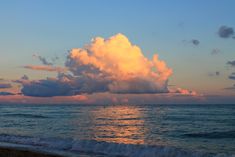 the sun is setting over the ocean and clouds are in the sky above the water