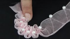 a woman's hand is holding a piece of fabric with pearls and mesh on it