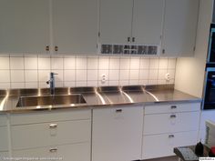 a kitchen with white cabinets and stainless steel counter tops