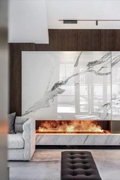 a modern living room with marble fireplace and couches in front of large windowed windows