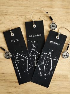 two black bookmarks with zodiac signs on them