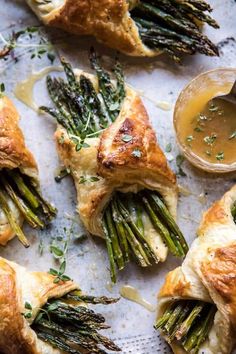 asparagus and cheese pastries on a sheet of parchment paper with dipping sauce