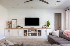 a living room with couches and a flat screen tv mounted on the wall above it