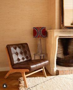 a brown chair sitting in front of a fire place next to a mirror on a wall