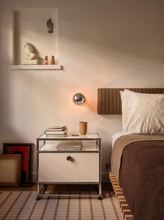 a bedroom with a bed, nightstand and lamp on the side table in front of it