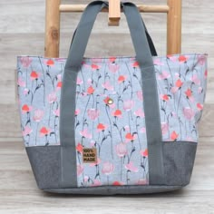 a gray and pink floral bag sitting on top of a wooden chair