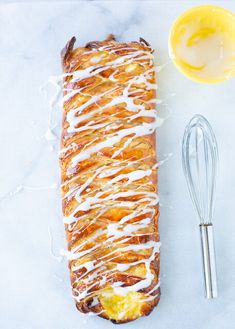 a loaf of bread with icing next to a whisk