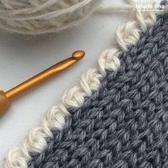 the crochet stitch is next to a ball of yarn and a knitting needle