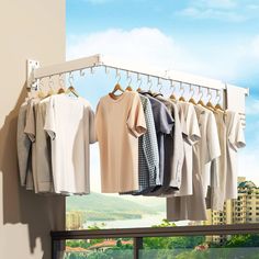 there are many shirts hanging on the clothes rack in front of a window with a city view