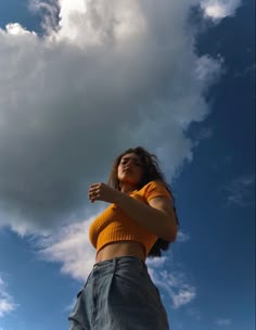 a woman is flying a kite in the blue sky with white clouds above her head