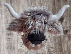 an animal's head is shown on a wooden surface with long horns and fur