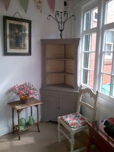 a chair and table in a room with two windows, one has pink flowers on it