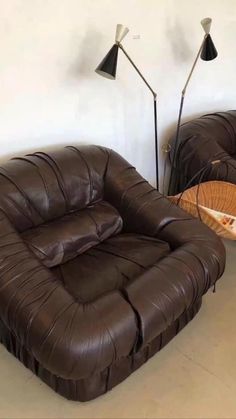 two brown leather couches sitting next to each other in a room with white walls