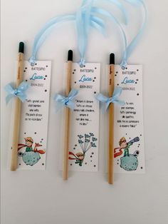 three toothbrushes with tags attached to them on a white surface, tied in blue ribbon