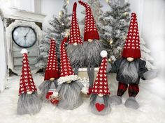 several gnome figurines sitting next to each other in front of a christmas tree